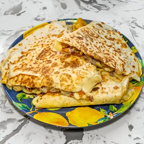 A plate of Tacos Don Chai quesadillas, filled with meat, cheese, and vegetables.