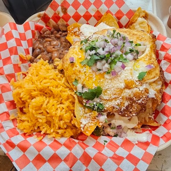 Mexican dish with rice, beans, and a large cheesy tortilla topped with onions and cilantro.