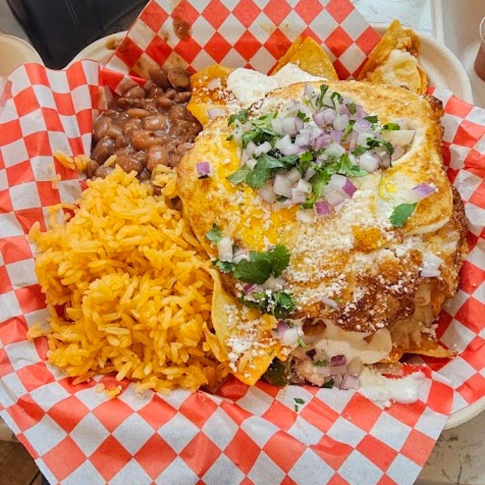 Mexican dish with rice, beans, and a large cheesy tortilla topped with onions and cilantro.